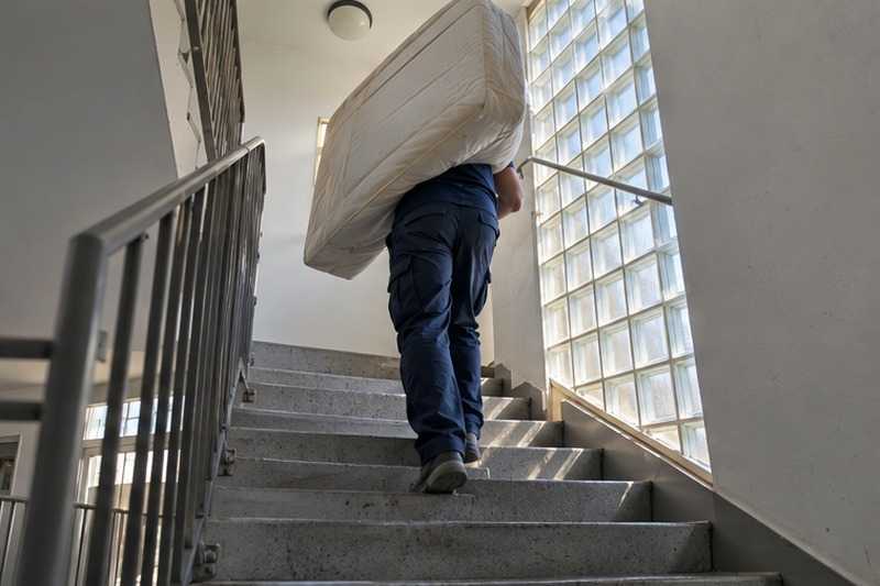 Matelas porté dans la cage d’escalier : chantier Rue Albert Schweitzer